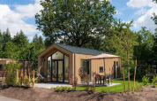 Smuk Tiny Lodge med varme karbad ved Veluwepark de Bosgraaf, omgivet af natur og grønne træer.
