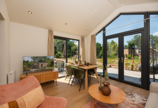 Bright interior of Tiny Lodge at Veluwepark de Bosgraaf, Netherlands, showing dining area and garden view.