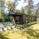 Moderne Forest Lodge Comfort med store vinduer og terrasse omgivet af frodig skov og grønne planter.