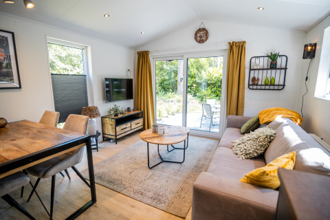 Woonkamer van Forest Lodge Comfort in Bospark Markelo, Nederland, met modern interieur en tuindeuren.
