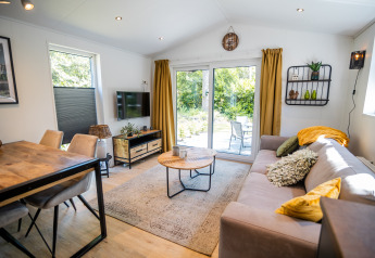 Salon de Forest Lodge Comfort au Bospark Markelo, Pays-Bas, décor moderne et grande baie vitrée sur le jardin.