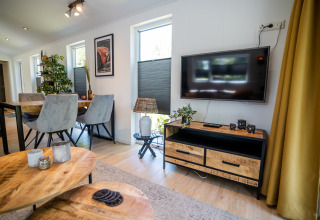 Soggiorno moderno con TV a schermo piatto, zona pranzo e arredo elegante nel Forest Lodge Comfort, Bospark Markelo.