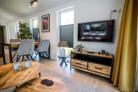 Soggiorno moderno con TV a schermo piatto, zona pranzo e arredo elegante nel Forest Lodge Comfort, Bospark Markelo.