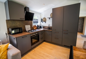 Cucina grigia moderna alla Forest Lodge Comfort presso Bospark Markelo, Paesi Bassi, con design elegante.