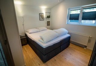 Schlafzimmer im Forest Lodge Comfort im Bospark Markelo, Niederlande, mit Doppelbett und moderner Einrichtung.