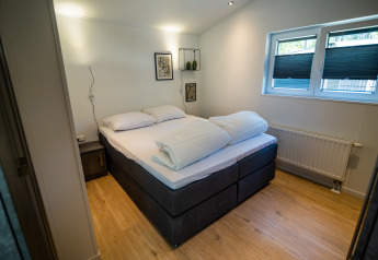 Camera da letto al Forest Lodge Comfort nel Bospark Markelo, Paesi Bassi, con letto matrimoniale e arredo moderno.
