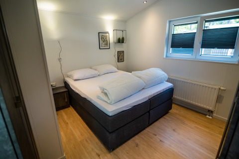 Schlafzimmer im Forest Lodge Comfort im Bospark Markelo, Niederlande, mit Doppelbett und moderner Einrichtung.
