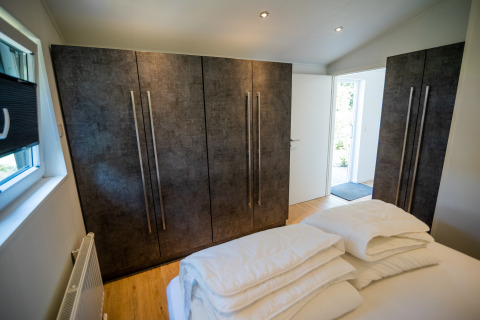 Slaapkamer met moderne kasten en opgestapeld beddengoed in Forest Lodge Comfort op Bospark Markelo, Nederland.