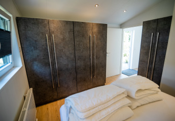 Schlafzimmer mit modernen Schränken und Bettwäsche in der Forest Lodge Comfort im Bospark Markelo, Niederlande.