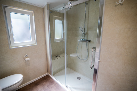 Moderne badkamer met douche, toilet en raam in Forest Lodge Comfort bij Bospark Markelo, Nederland.