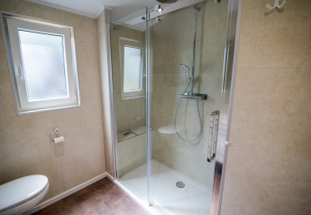 Moderne badeværelse med bruser, toilet og vindue på Forest Lodge Comfort i Bospark Markelo, Holland.