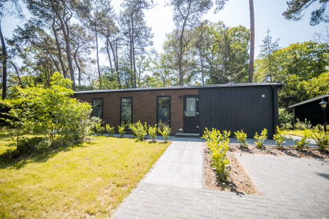 Forest Lodge Comfort at Bospark Markelo in the Netherlands, surrounded by trees and a landscaped garden.