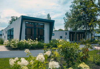 Moderne lodge Just Nature omgeven door bloemen en planten, gelegen in een rustige, groene omgeving.