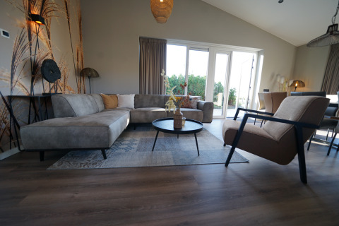 Modern living room at Just Nature lodge in De Utrechtse Heuvelrug, Netherlands, with bright furniture and windows.