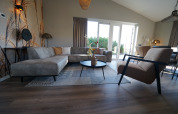 Modern living room at Just Nature lodge in De Utrechtse Heuvelrug, Netherlands, with bright furniture and windows.