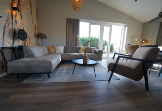 Modern living room at Just Nature lodge in De Utrechtse Heuvelrug, Netherlands, with bright furniture and windows.