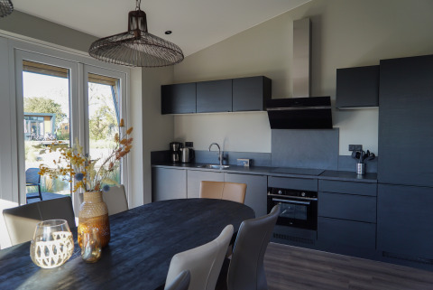 Modern kitchen and dining table at Just Nature lodge in De Utrechtse Heuvelrug, Netherlands, with large windows.