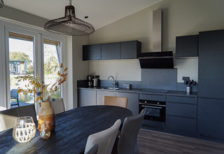 Modern kitchen and dining table at Just Nature lodge in De Utrechtse Heuvelrug, Netherlands, with large windows.