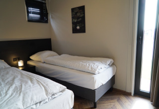 Cozy lodge room with two single beds, a bedside lamp, wall art, and natural light coming through a window.