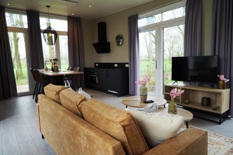 Modern lodge living room at Just Nature, De Utrechtse Heuvelrug, Netherlands, with cozy decor and large windows.