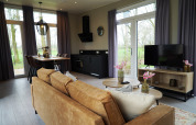Moderne lodge woonkamer bij Just Nature, De Utrechtse Heuvelrug, Nederland, met grote ramen en gezellig interieur.