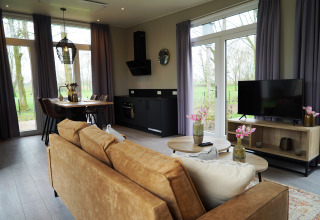 Modern lodge living room at Just Nature, De Utrechtse Heuvelrug, Netherlands, with cozy decor and large windows.