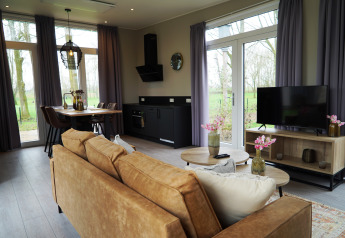 Moderne lodge woonkamer bij Just Nature, De Utrechtse Heuvelrug, Nederland, met grote ramen en gezellig interieur.