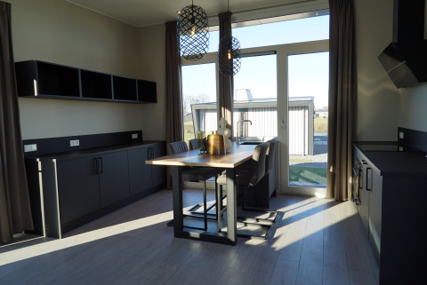 Modern kitchen and dining area at Just Nature Lodge, De Utrechtse Heuvelrug, Netherlands, with large windows.