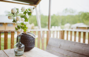 En vase med hvide blomster på et træbord på terrassen af Safari teltet ved Club Les Ormes, Frankrig.