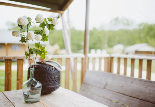 Un vaso con fiori bianchi su un tavolo di legno nella veranda della tenda Safari al Club Les Ormes, Francia.