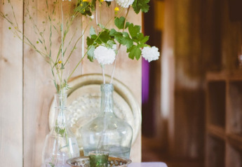 En dekoreret lille bord med glasvaser med hvide blomster og metal-skål i et safari telt i Club Les Ormes, Frankrig.