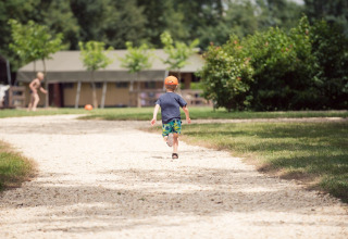 Un bambino corre su un sentiero ghiaioso davanti a una tenda safari a Club Les Ormes in Francia.