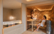 Wellness Suite at Woodz Lodges, Belgium, featuring two people in a sauna and a stylish indoor fireplace.