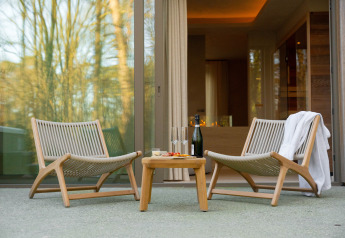 Zwei Outdoor-Stühle und ein Tisch mit Sekt vor der Wellness Suite im Woodz Lodges, Belgien im Frühling.