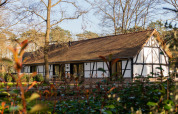 Traditionel hytte med rødt tegltag og bindingsværk, omgivet af træer ved Villa Lodge, Woodz Lodges, Belgien.