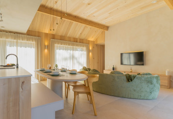 Moderne leefruimte in Villa Lodge met jacuzzi bij Woodz Lodges in België, lichte houten inrichting.