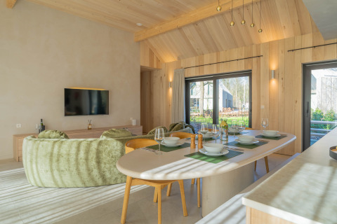 Moderne en lichtrijke woonruimte met eethoek in Villa Lodge met jacuzzi bij Woodz Lodges, België.