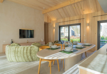 Moderne en lichtrijke woonruimte met eethoek in Villa Lodge met jacuzzi bij Woodz Lodges, België.