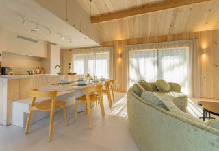 Lichte, moderne leefruimte in Villa Lodge met jacuzzi bij Woodz Lodges, België, met houten interieur.