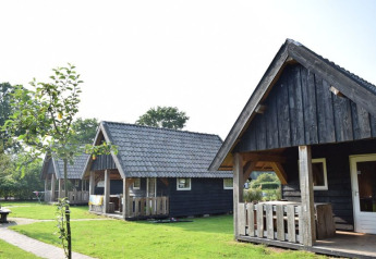 Lodge in legno al Wood Lodge, ciascuna con veranda e tetto spiovente, immerse nel verde e alberi attorno.