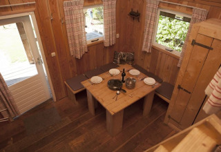 Interior de cabaña de madera con mesa de comedor y bancos en Holiday park De Boshoek, Países Bajos.