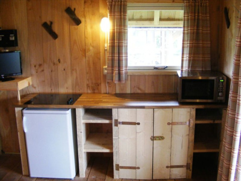 Coin cuisine en bois au Wood Lodge, Holiday park De Boshoek, avec frigo, micro-ondes et fenêtre.