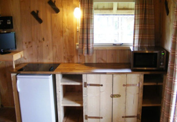 Coin cuisine en bois au Wood Lodge, Holiday park De Boshoek, avec frigo, micro-ondes et fenêtre.