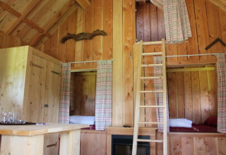Interior de madera de Wood Lodge en Holiday park De Boshoek, Países Bajos, con literas y escalera.