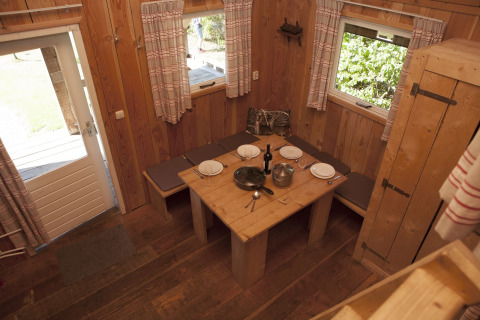 Houten eethoek in Wood Lodge van Holiday park De Boshoek, Nederland, met gedekte tafel en banken.