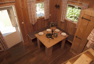 Acogedor comedor de madera en Wood Lodge, Holiday park De Boshoek, Países Bajos, con mesa y bancos preparados.