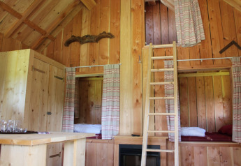 Innenraum der Wood Lodge im Holiday park De Boshoek mit Holzwänden, Betten und einer Leiter.