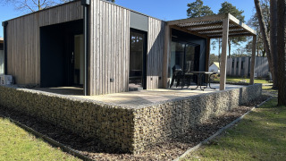 Domus 4+2 Lodge mit moderner Holzverkleidung, großer Terrasse und Outdoor-Bereich in der Natur.