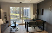 Modern Domus 4+2 lodge at Zilverstrand in Belgium, featuring a sleek living and dining area with large windows.