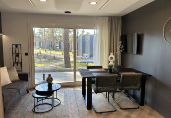 Moderne lodge Domus 4+2 op Zilverstrand in België, met stijlvolle woonkamer, eetruimte en tuinzicht.
